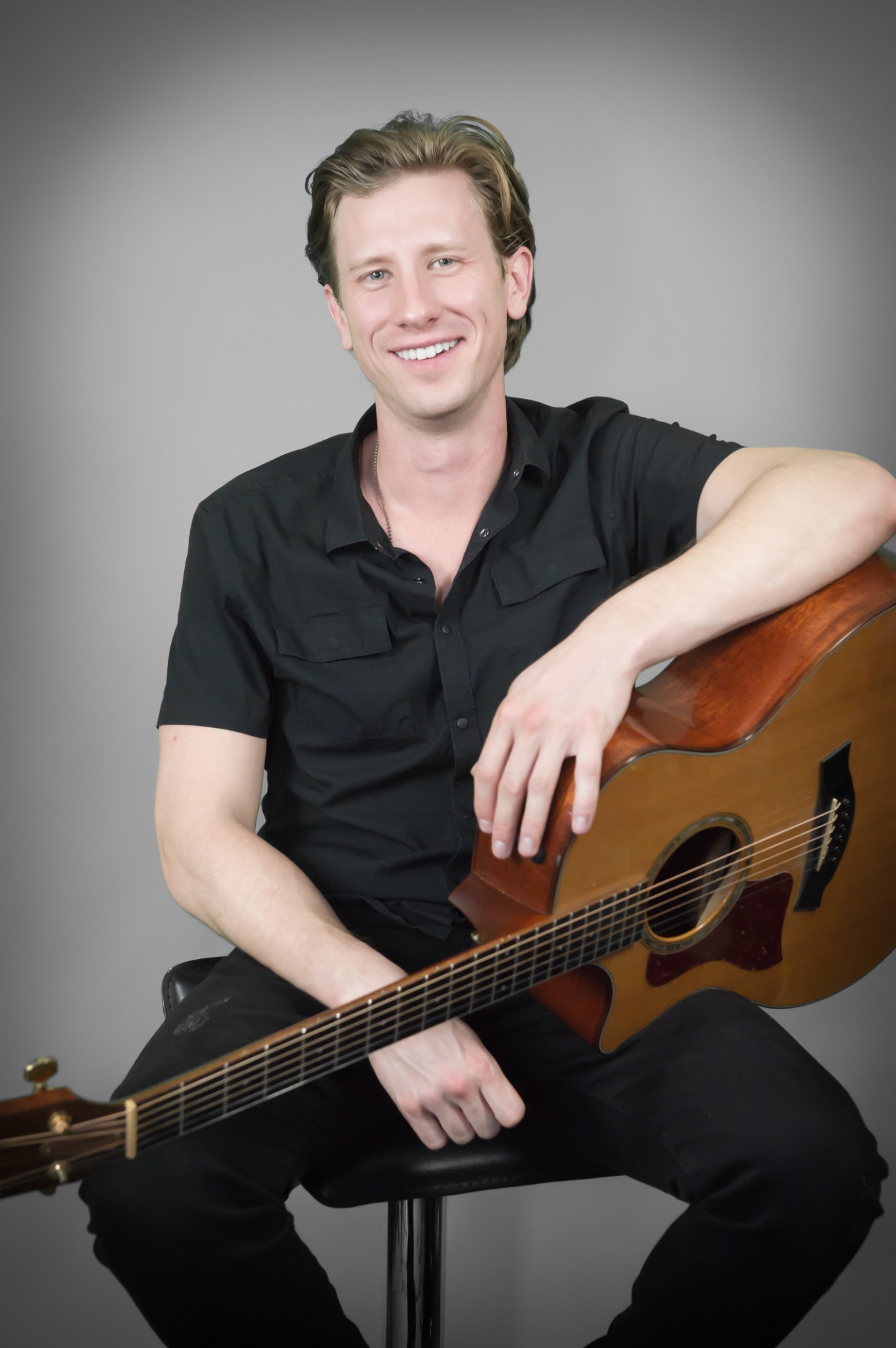David Hadley smiling with an acoustic guitar